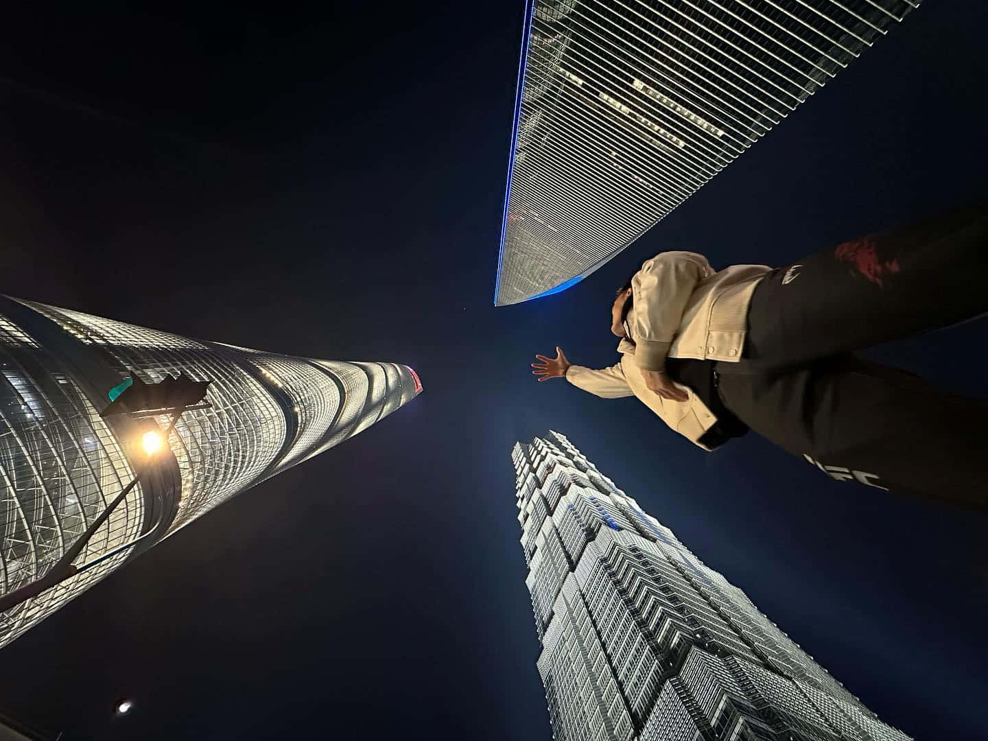 Skyscraper 桌布 壁紙 — 一個人在漆黑的夜空下，漂浮在摩天大樓之間，窗戶發光，帶有藍色霓虹燈點綴。