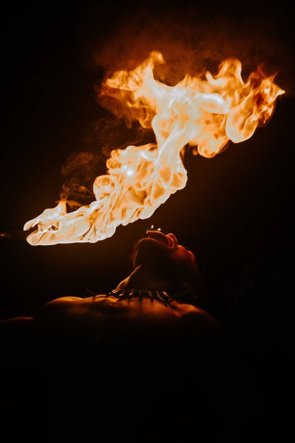 著火 桌布 壁紙 — 一個人在漆黑背景前呼出一股橙白相間的戲劇性火焰。