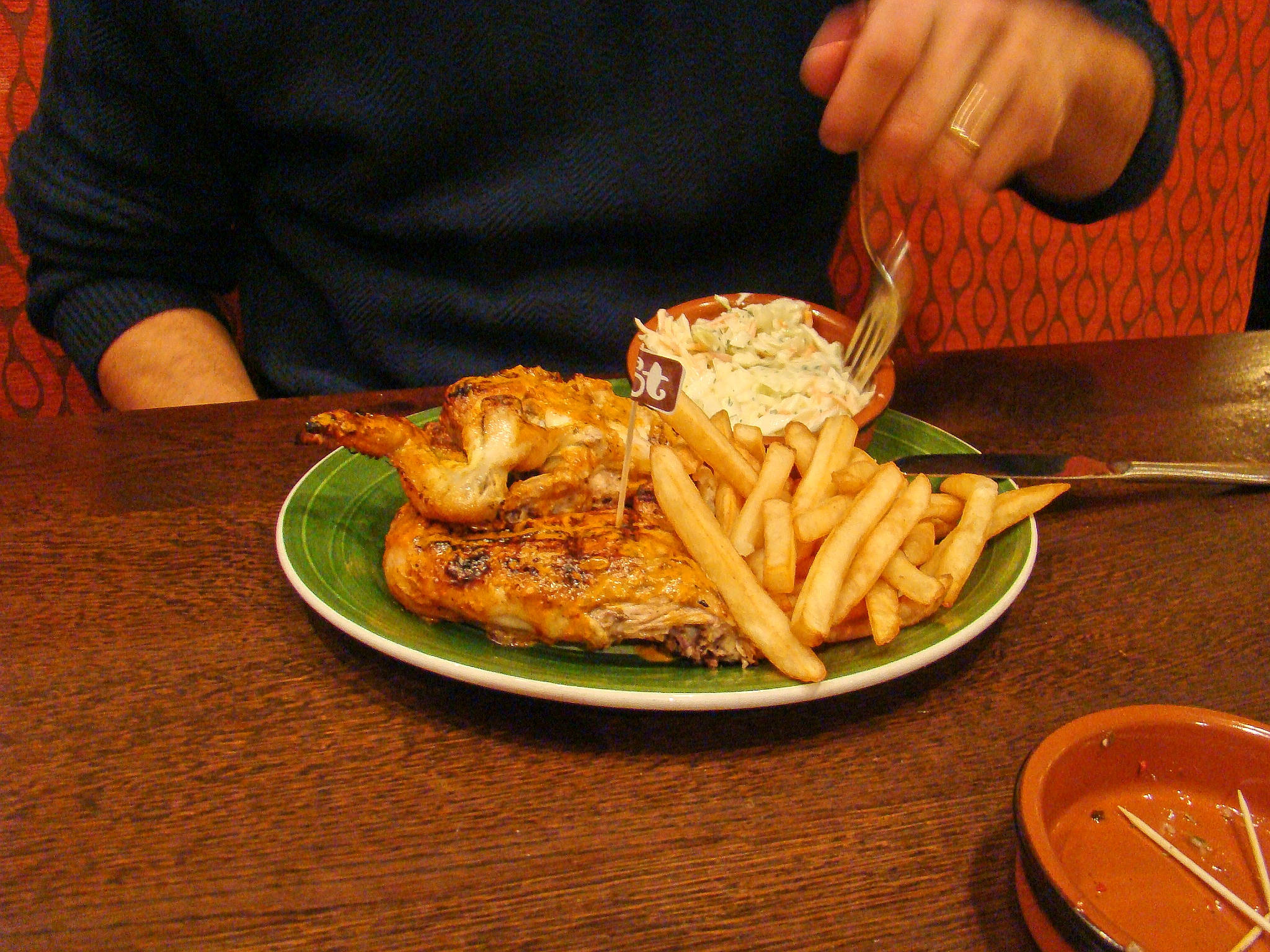 Delicious Food 桌布 壁紙 — 一個人在燈光溫暖的餐廳裡，從木桌上綠色盤子中吃烤雞和薯條。