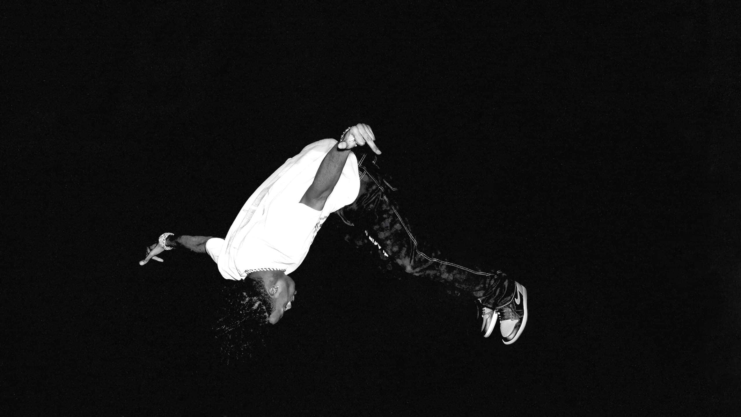 Playboi Carti 桌布 壁紙 — 一個人在空中以動感霹靂舞姿勢，襯托單色純黑背景。