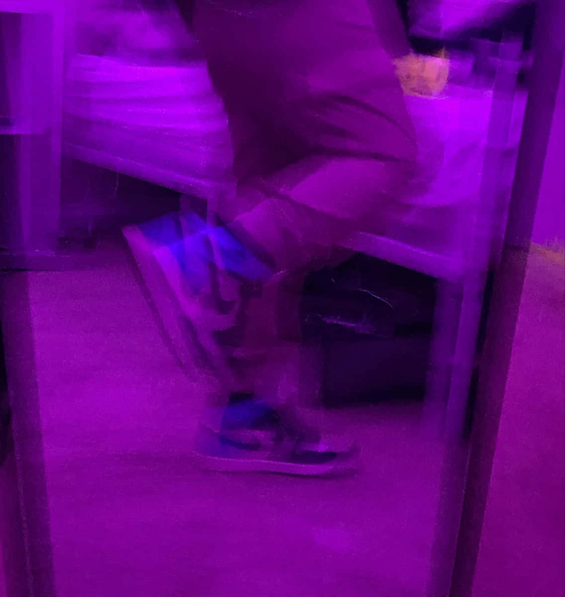 鞋子 桌布 壁紙 — 一個人在紫色燈光下坐著，動作模糊，運動鞋在地毯上可見。