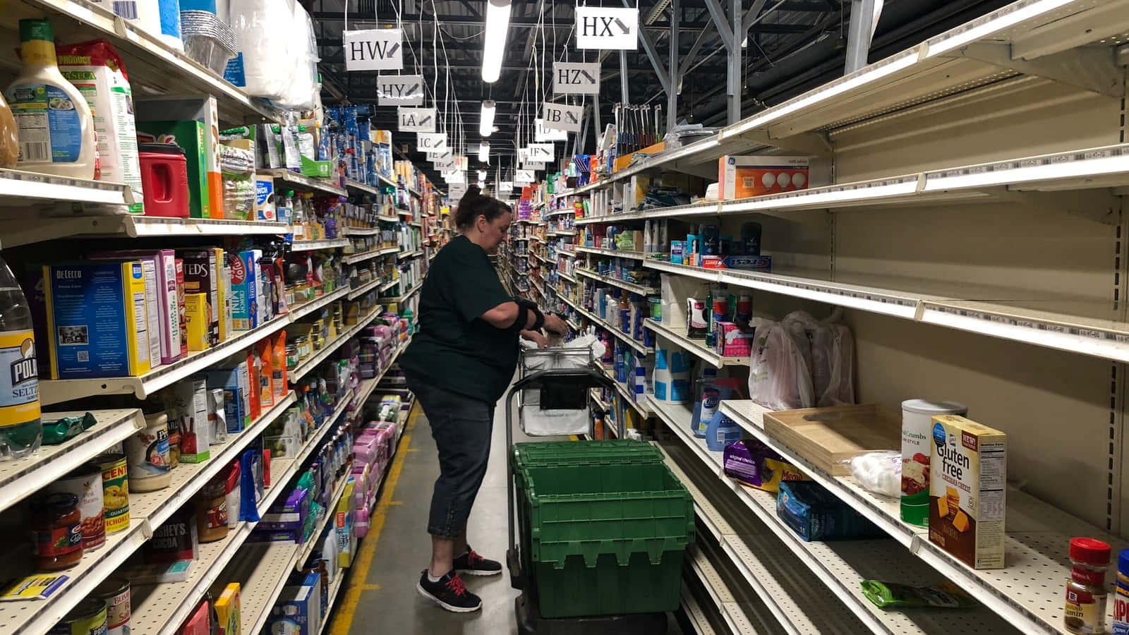 Shopping 桌布 壁紙 — 一個人在超市的長走廊上推著購物車，貨架大部分是空的，商品散落一地。