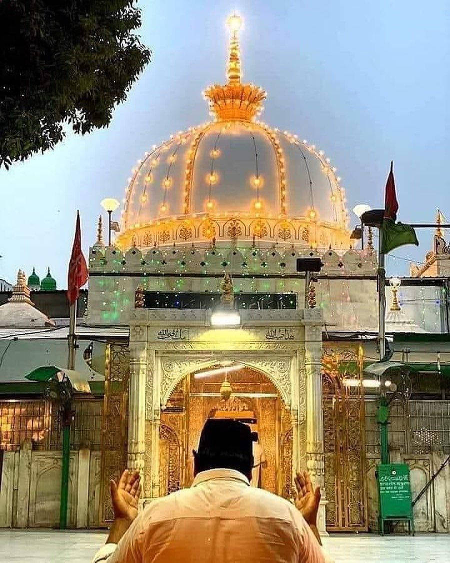 muslim 桌布 壁紙 — 一個人在黃昏時分，在宏偉的金色圓頂清真寺前祈禱，清真寺被溫暖的燈光和精緻的雕刻照亮。