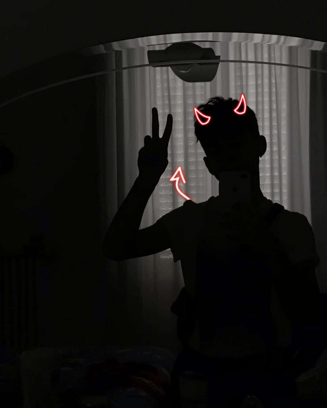 Silhouette 桌布 壁紙 — 一個人在黑暗房間中的剪影做出和平手勢，而發光的紅色惡魔角和箭頭裝飾著他們的頭部，在鏡子自拍中。