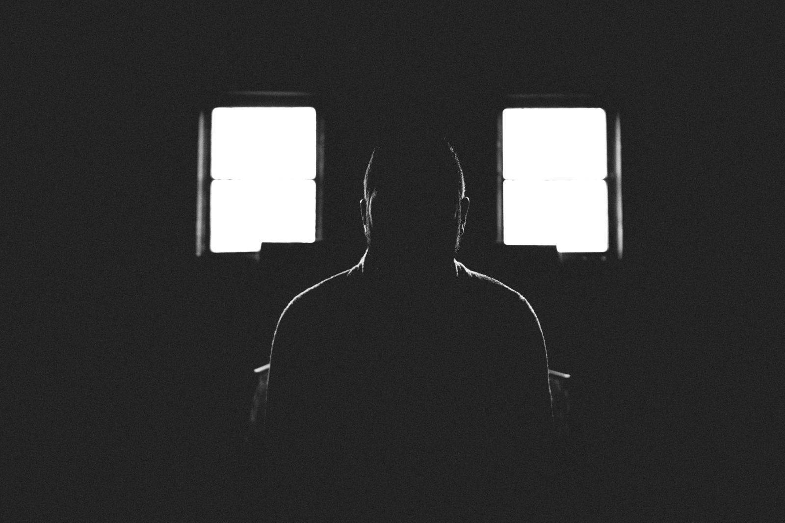 Silhouette 桌布 壁紙 — 一個人在黑暗房間中站在兩個明亮窗戶之間的剪影。