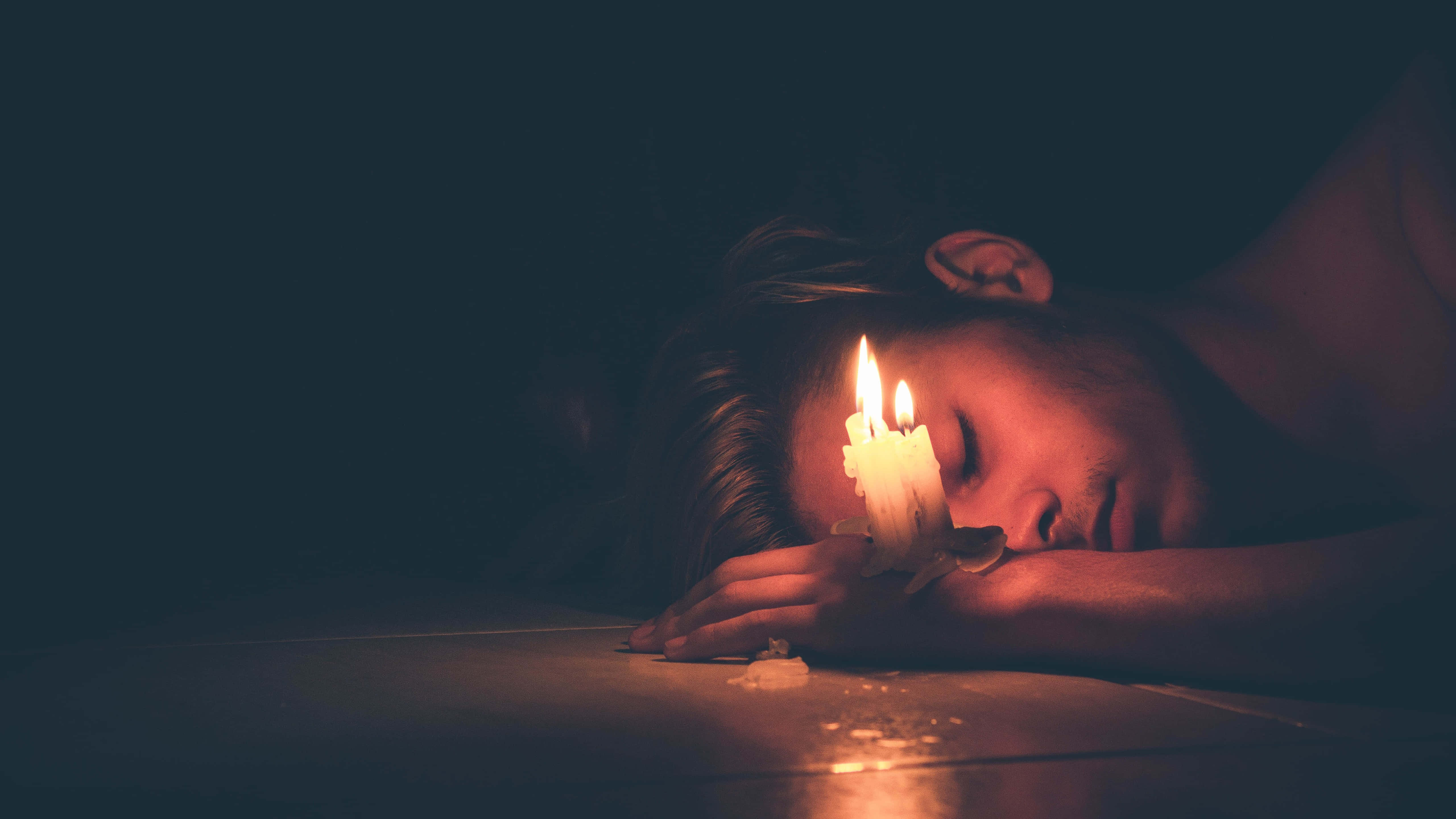 Alone 桌布 壁紙 — 一個人在黑暗的房間裡，額頭上放著一根點燃的蠟燭，安詳地睡著。