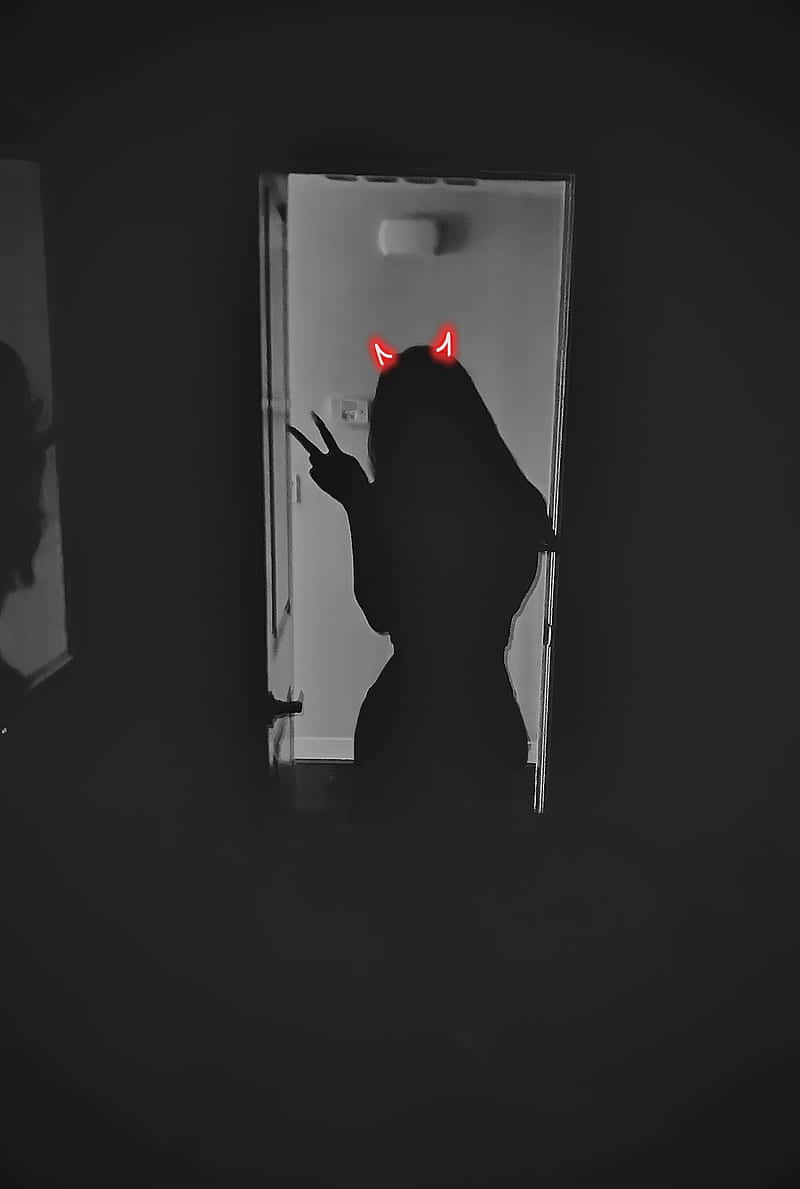 Silhouette 桌布 壁紙 — 一個人在黑暗門口中，帶有發光紅色惡魔角和和平手勢的剪影。