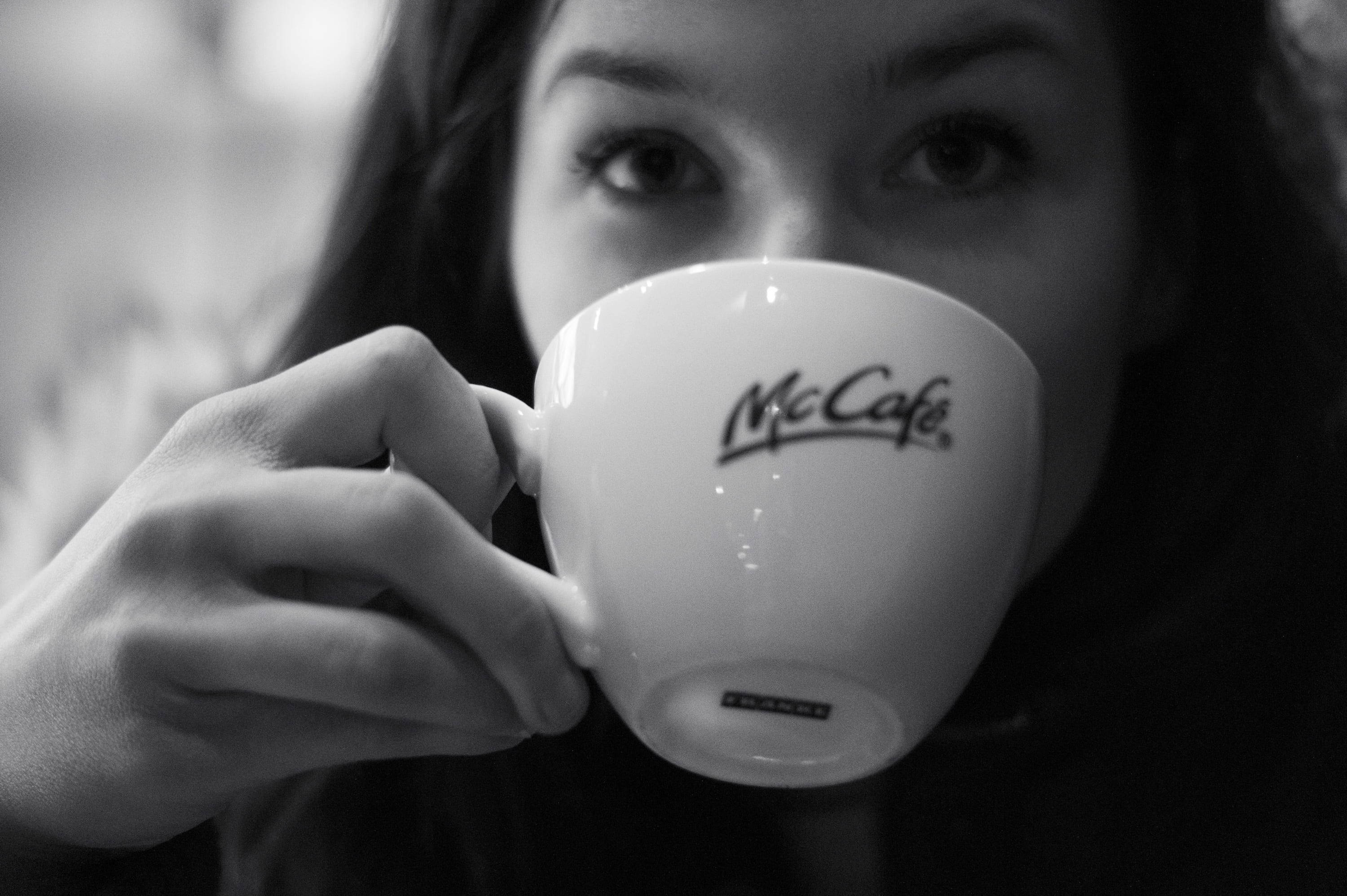 Mcdonalds 桌布 壁紙 — 一個人在黑白特寫鏡頭中將McCafé杯舉到嘴唇邊。