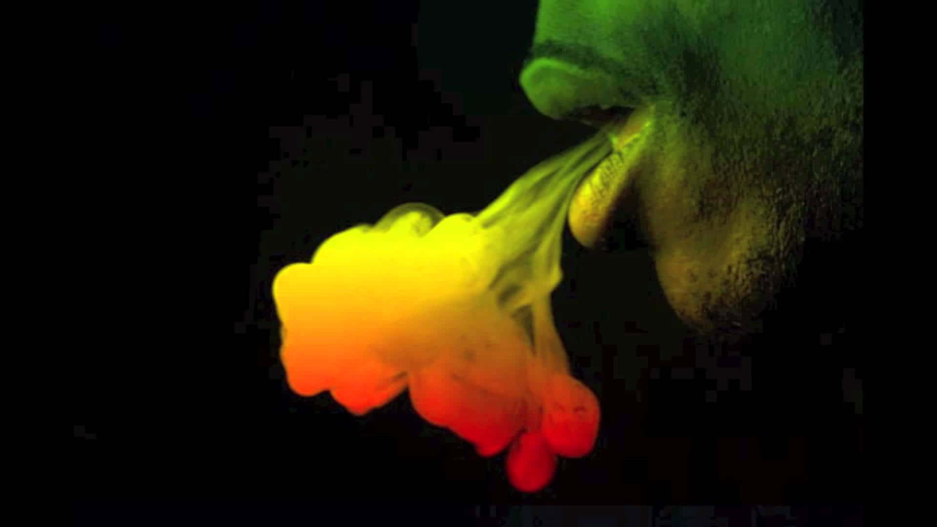 Rasta 桌布 壁紙 — 一個人在黑色背景前呼出一團從黃色到紅色發光的鮮豔漸變煙霧。