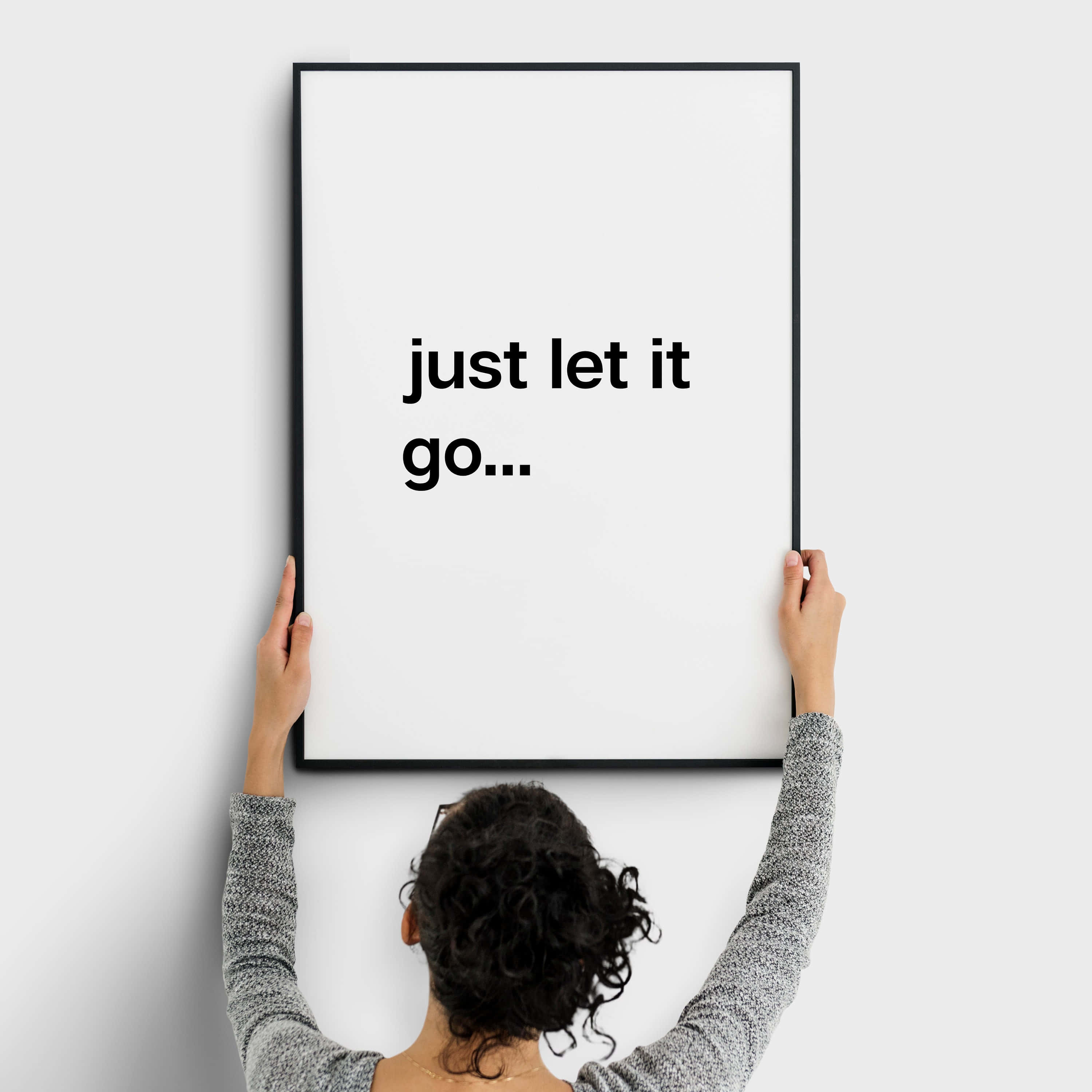 let it go 桌布 壁紙 — 一個人將一張極簡黑色邊框海報掛在純白牆上，海報上寫著 just let it go...