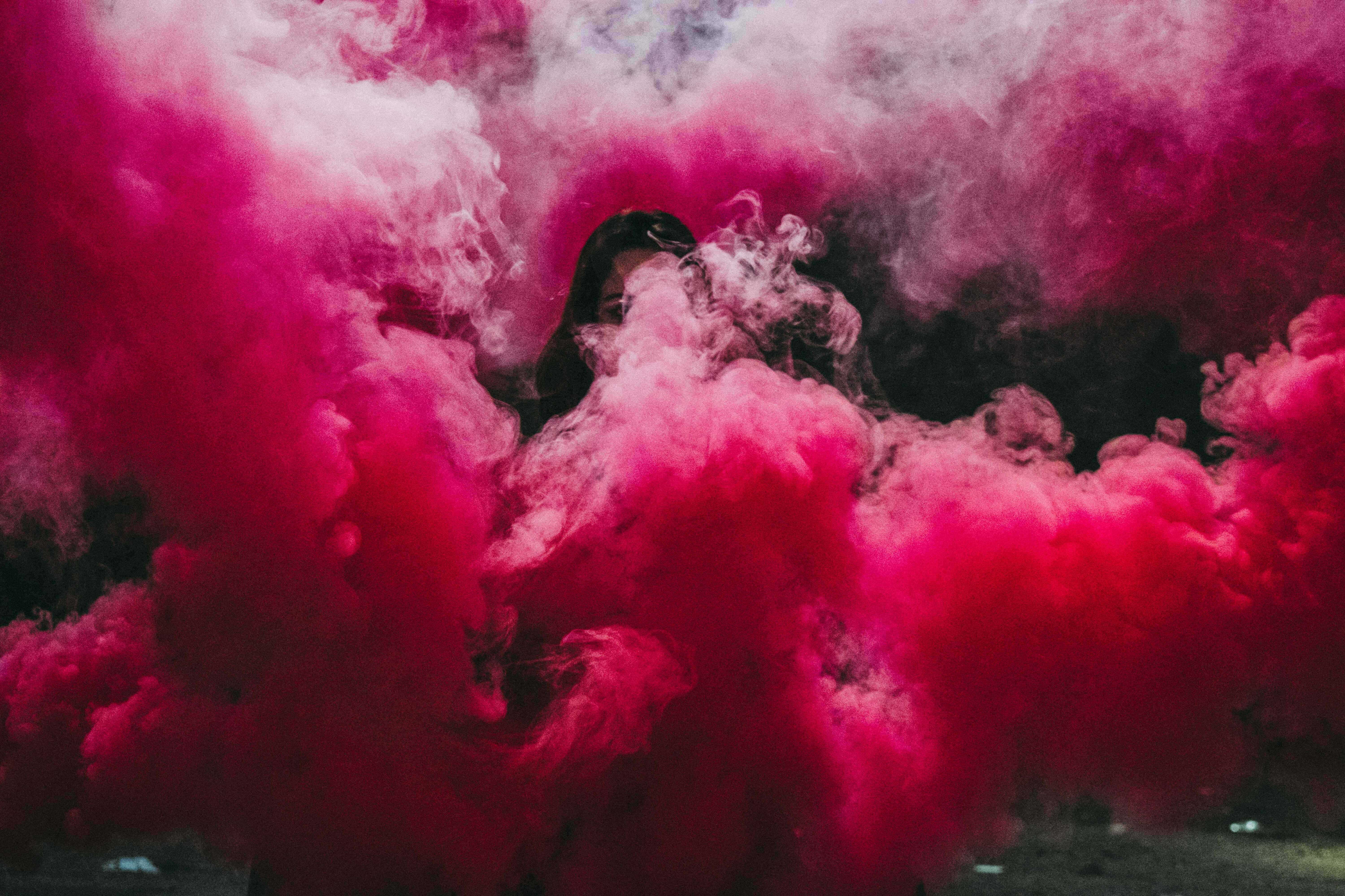 Pink Smoke 桌布 壁紙 — 一個人從旋轉的鮮豔粉紅色煙霧中出現，背景為深色。