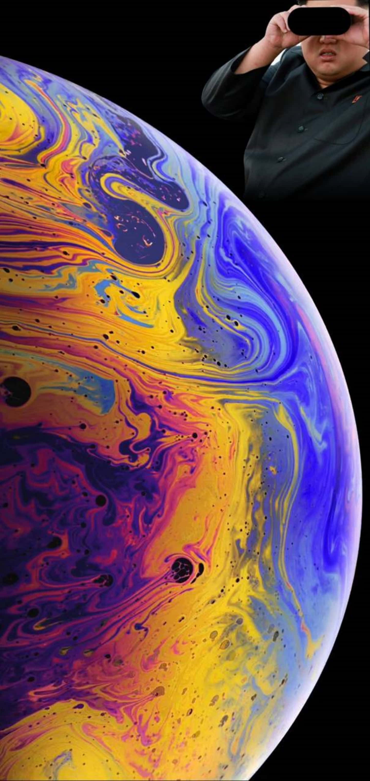 Galaxy S10 Plus 桌布 壁紙 — 一個人戴著VR頭戴式顯示器，凝視著一個在黑色虛空中旋轉、充滿鮮豔黃色、紫色和藍色的宇宙球體。