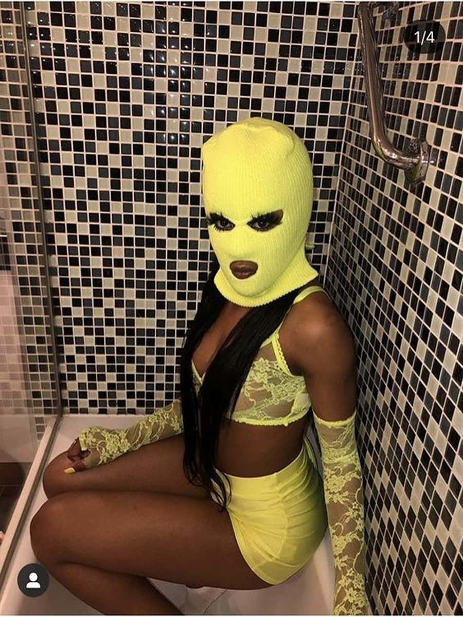 Ski Mask Girl 桌布 壁紙 — 一個人戴著亮黃色針織面罩和相配服裝，坐在黑白瓷磚牆的淋浴間裡。