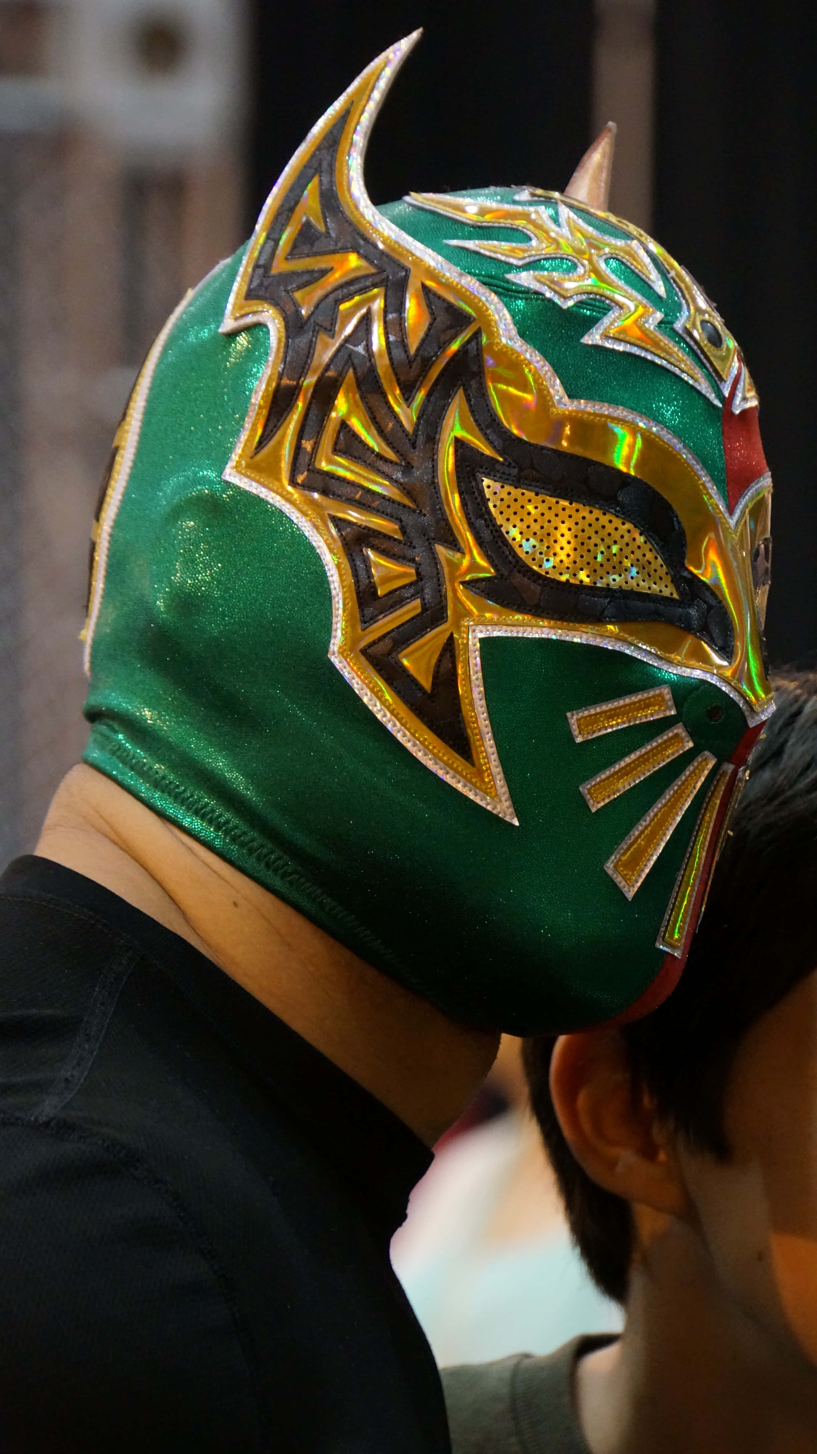 WWE 桌布 壁紙 — 一個人戴著充滿活力的綠色和金色 lucha libre 面具，帶有複雜的圖案和金屬裝飾。