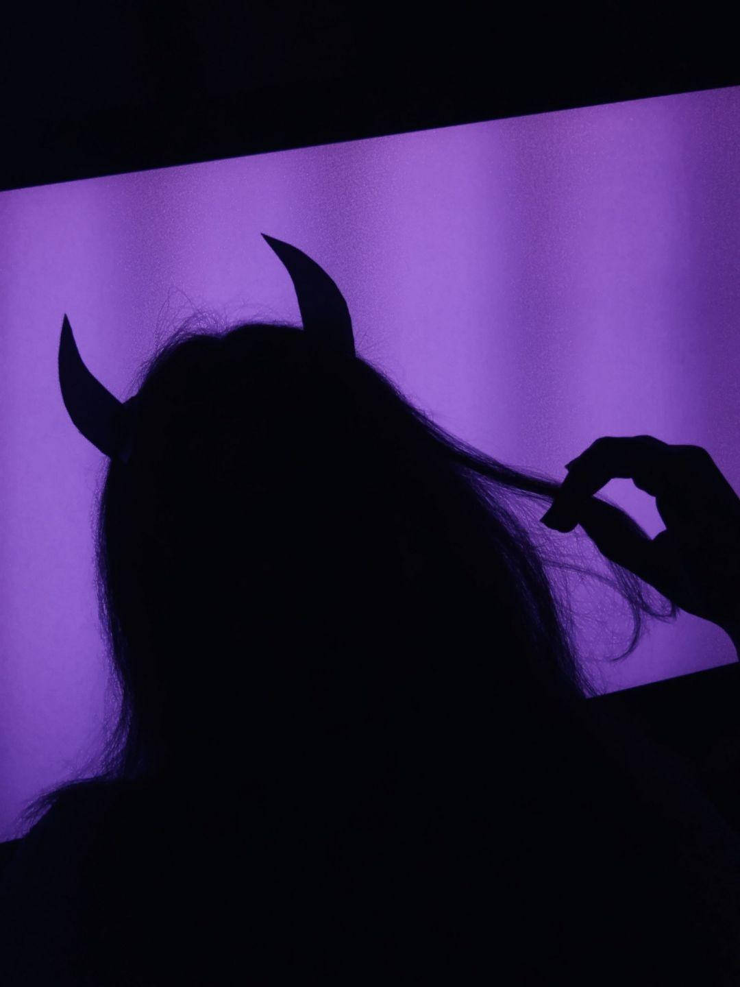 Devil Horns 桌布 壁紙 — 一個人戴著惡魔角剪影，背景是發光的紫色，手輕輕觸摸頭髮。