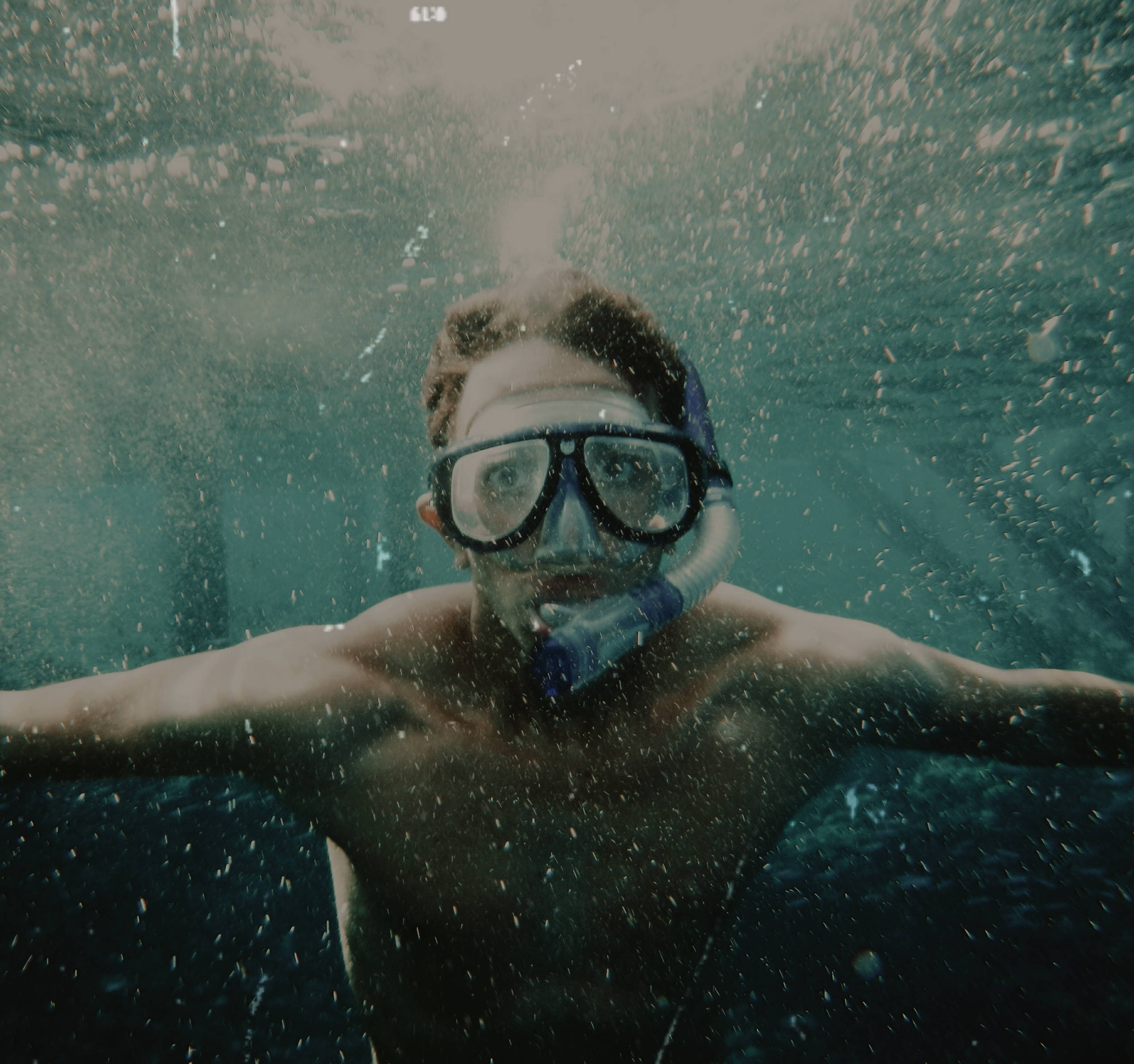 Snorkeling 桌布 壁紙 — 一個人戴著潛水面罩在渾濁的綠色水中游泳，周圍有浮游粒子。