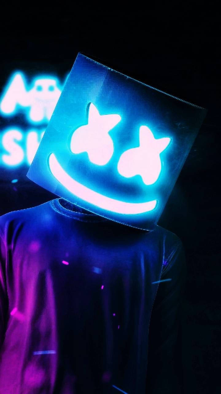 Marshmello 動態圖 桌布 壁紙 — 一個人戴著發光的藍色方形面具，面具上有笑臉，站在黑暗中，周圍有霓虹紫和藍色燈光。