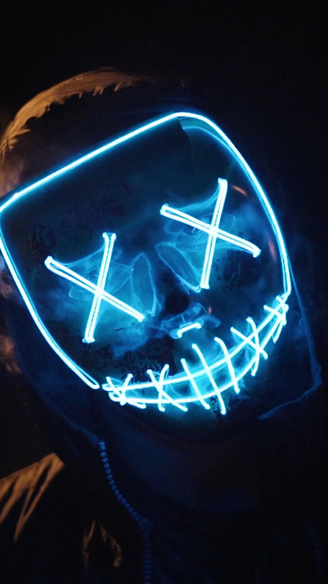 marshmello iPhone 桌布 壁紙 — 一個人戴著發光藍色LED面具，有X眼睛和縫合嘴巴，背景為深色。