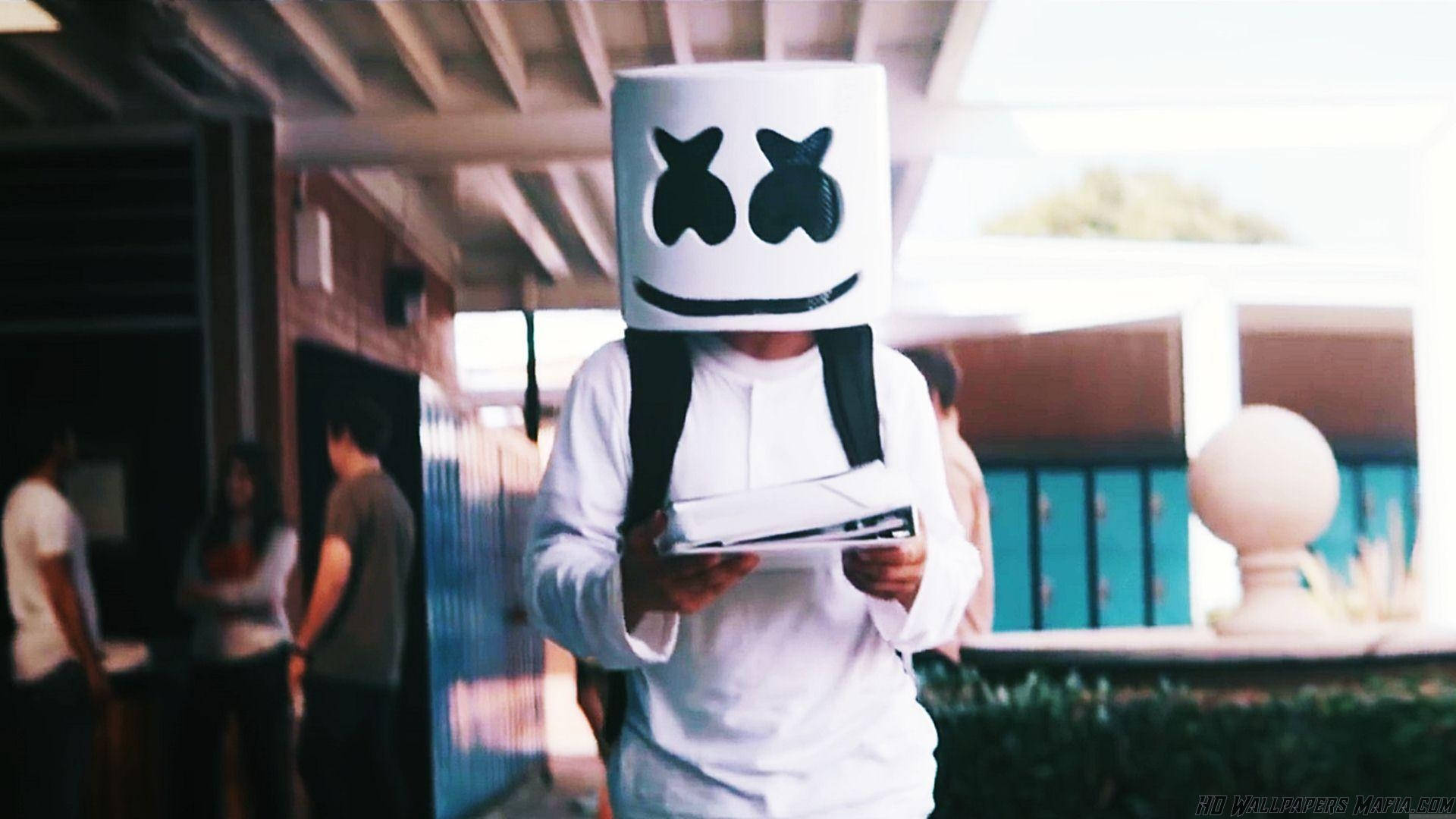 Marshmello 動態圖 桌布 壁紙 — 一個人戴著白色棉花糖面具，有黑色眼睛和微笑，在有蓋走道下拿著平板電腦。
