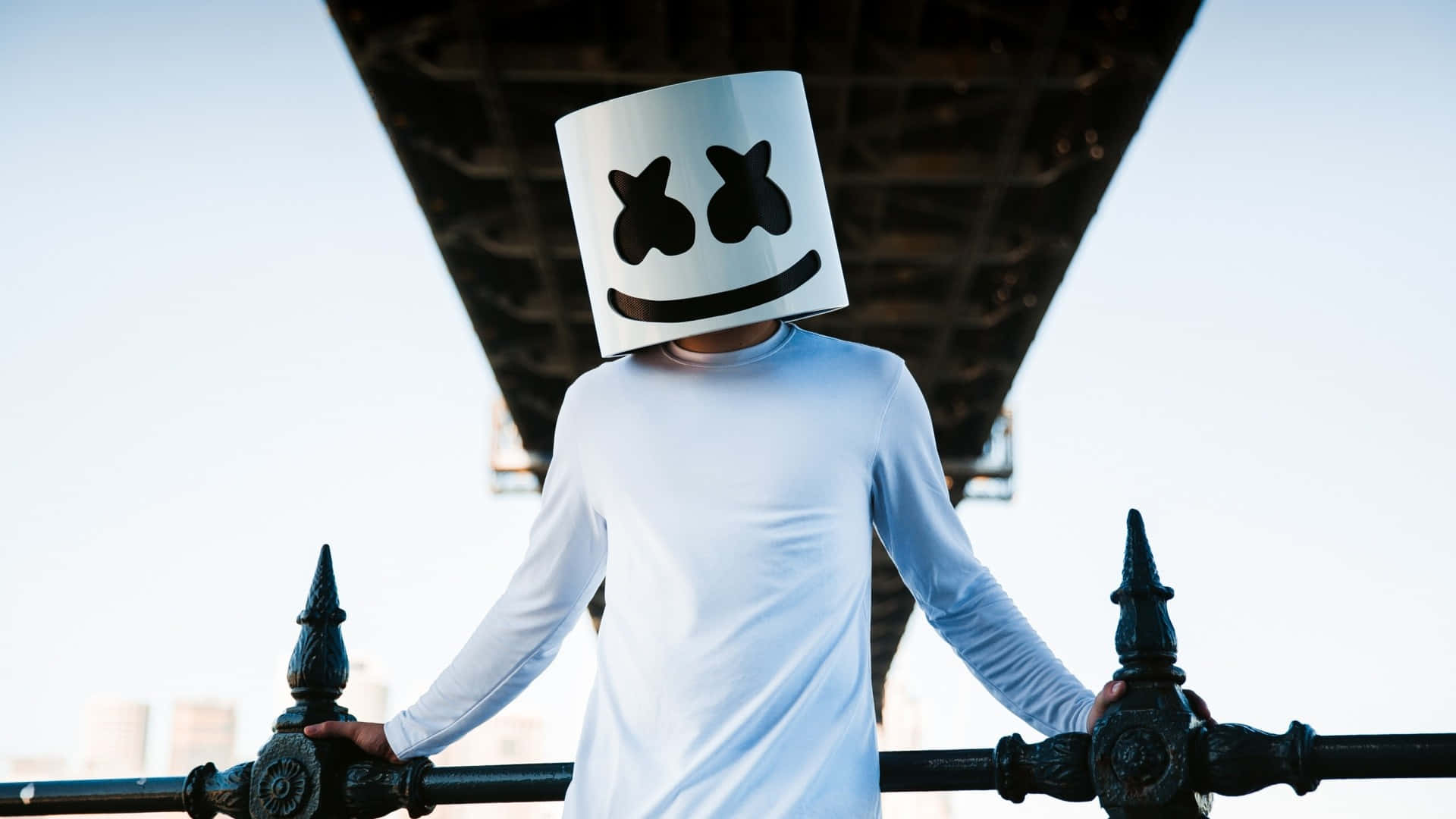 Marshmello 動態圖 桌布 壁紙 — 一個人戴著白色棉花糖頭盔，站在橋欄杆下，背景是明亮的天空。