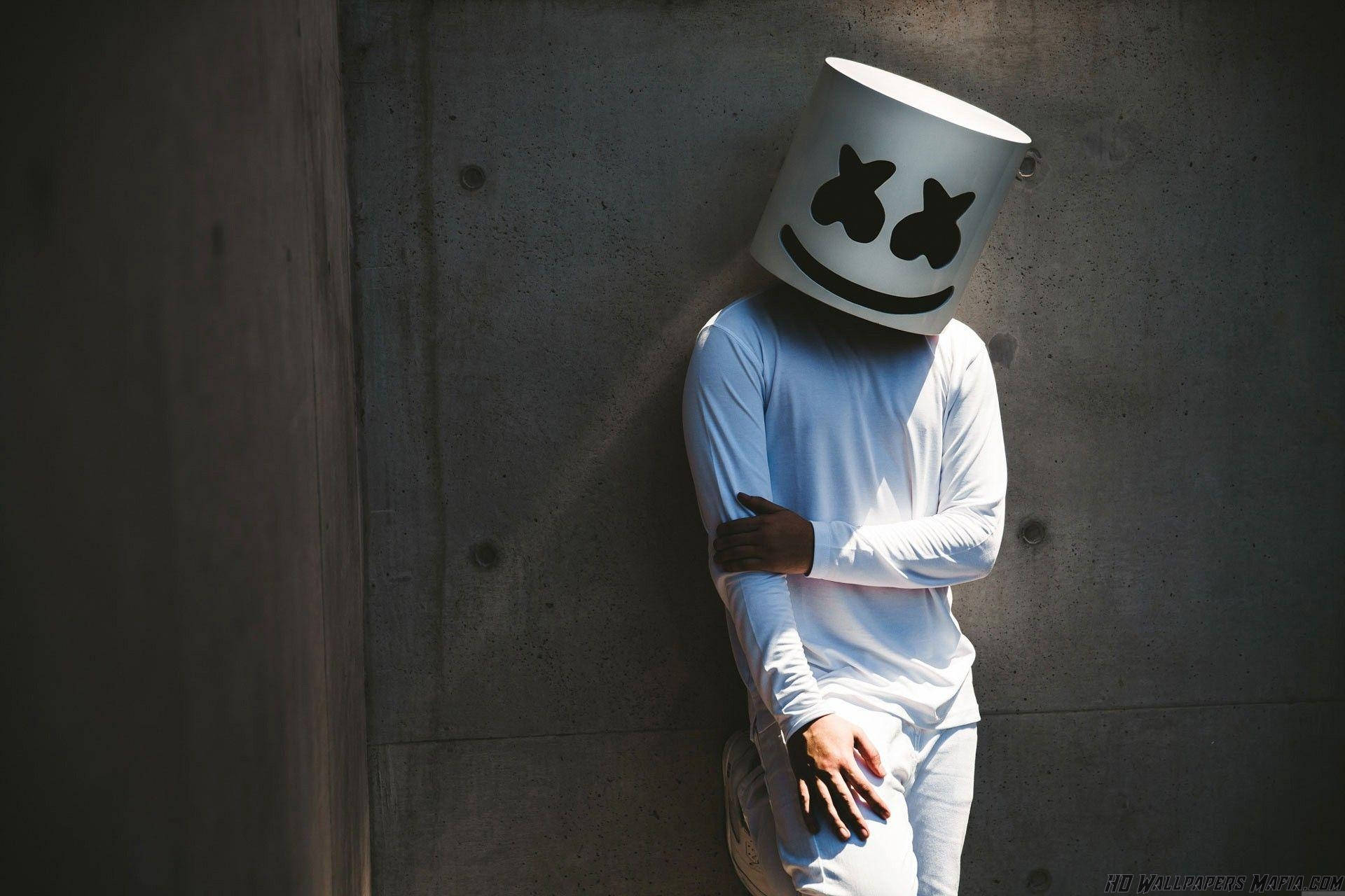 Marshmello 動態圖 桌布 壁紙 — 一個人戴著白色棉花糖頭盔，靠著沐浴在明亮陽光下的混凝土牆。