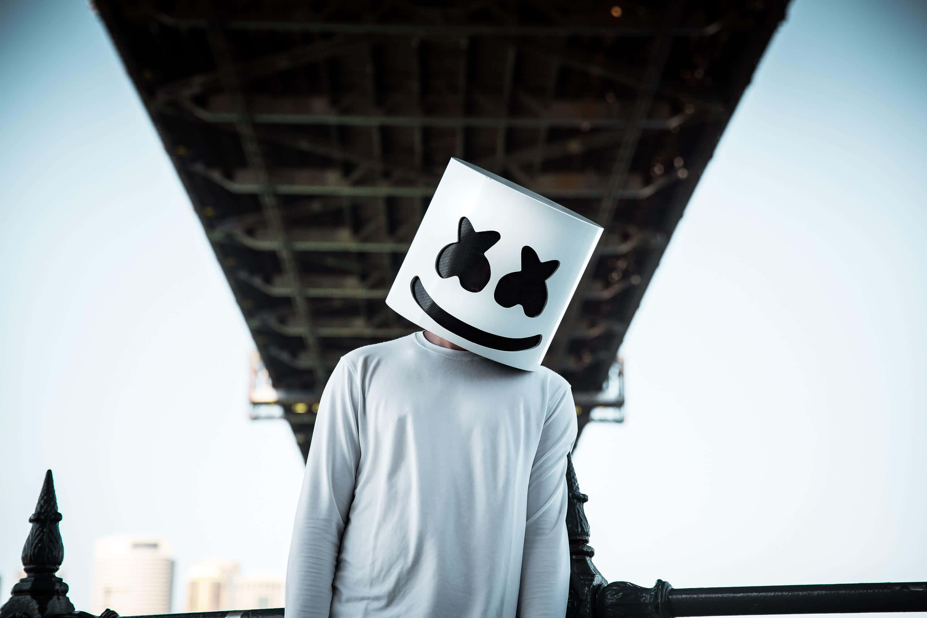 Marshmello 動態圖 桌布 壁紙 — 一個人戴著白色棉花糖頭盔站在橋下，背景是城市天際線。