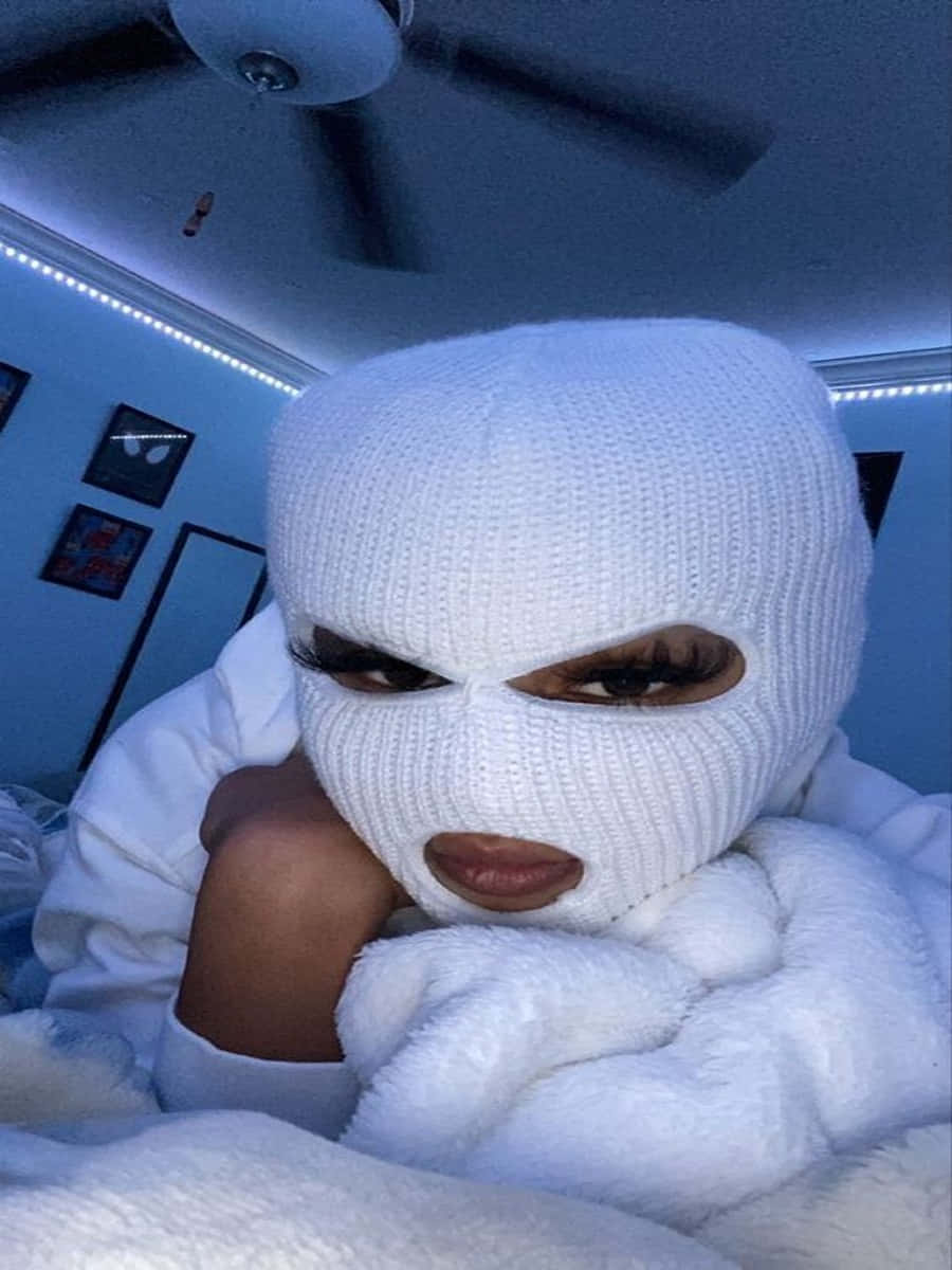 Ski Mask Girl 桌布 壁紙 — 一個人戴著白色針織巴拉克拉法帽和毛絨白色睡袍，在昏暗的房間裡放鬆，房間裡有藍色LED燈。
