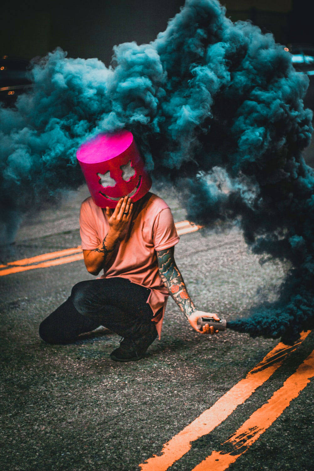 人跪在街上手持煙霧裝置戴著粉紅色笑臉桶形頭盔。 — 單身男孩 壁紙