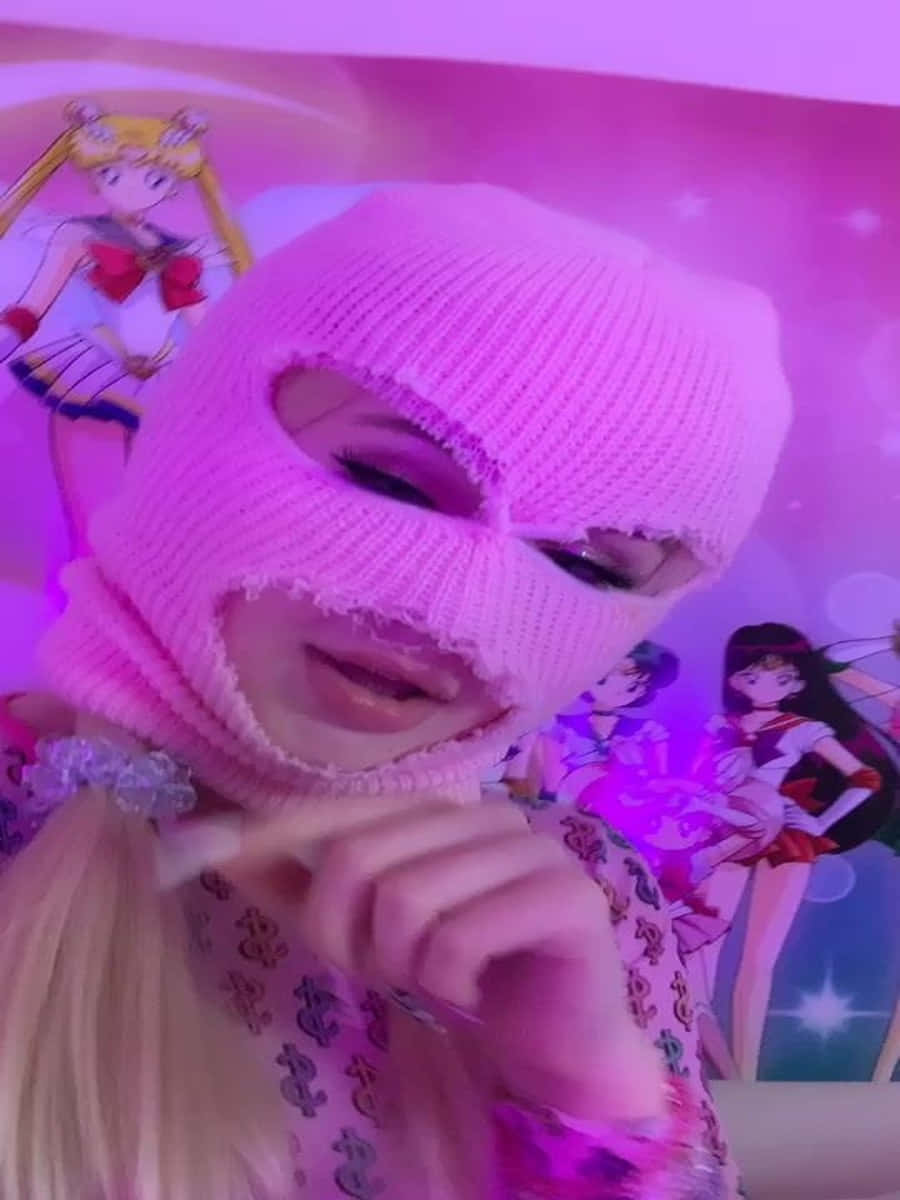 Ski Mask Girl 桌布 壁紙 — 一個人戴著粉紅色針織巴拉克拉法帽，在充滿閃粉的粉紅色美少女戰士壁紙前擺姿勢。