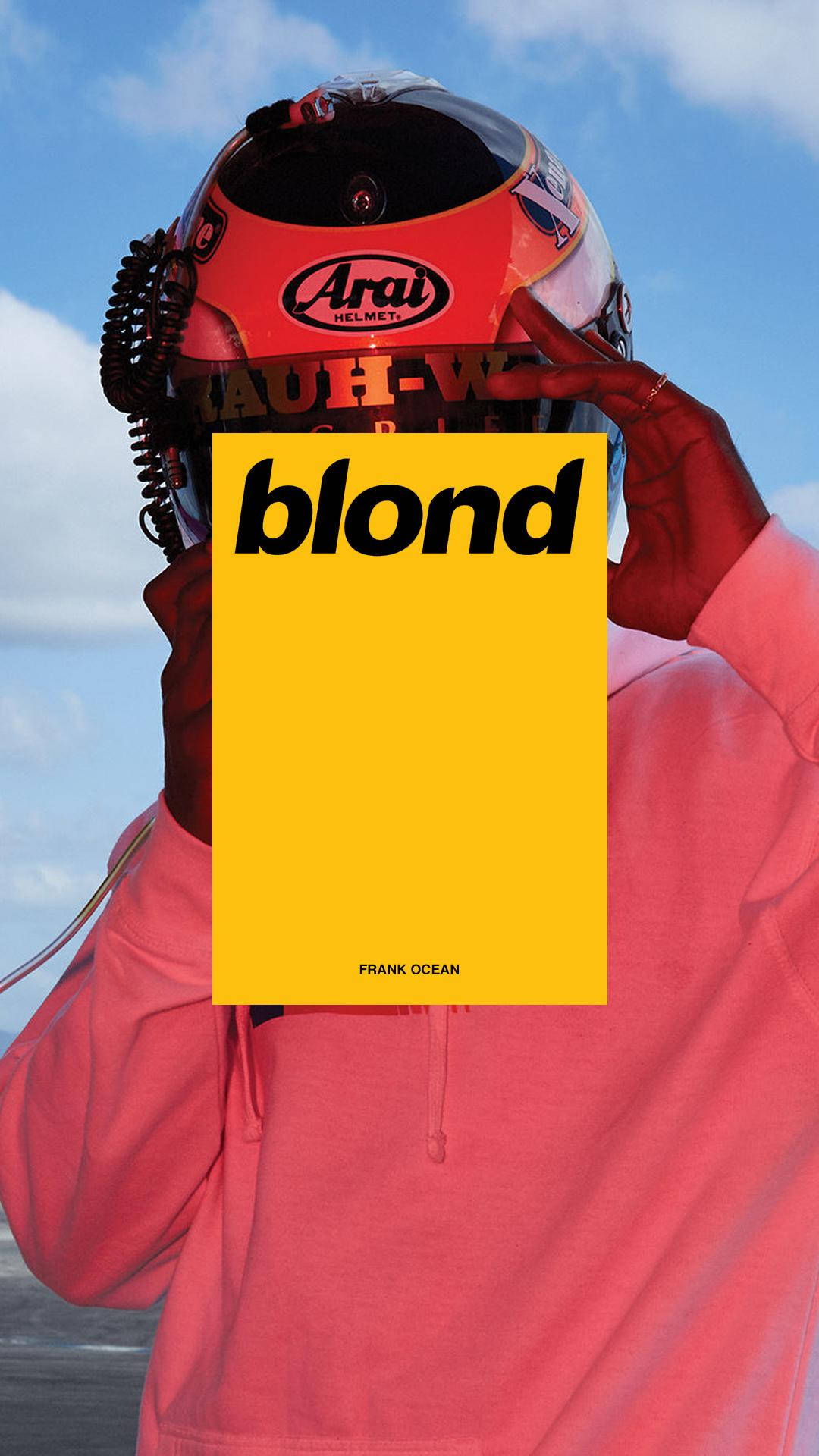 Frank Ocean 桌布 壁紙 — 一個人戴著賽車頭盔和粉紅色連帽衫，手持Frank Ocean的黃色專輯封面《blond》，背景是藍天。