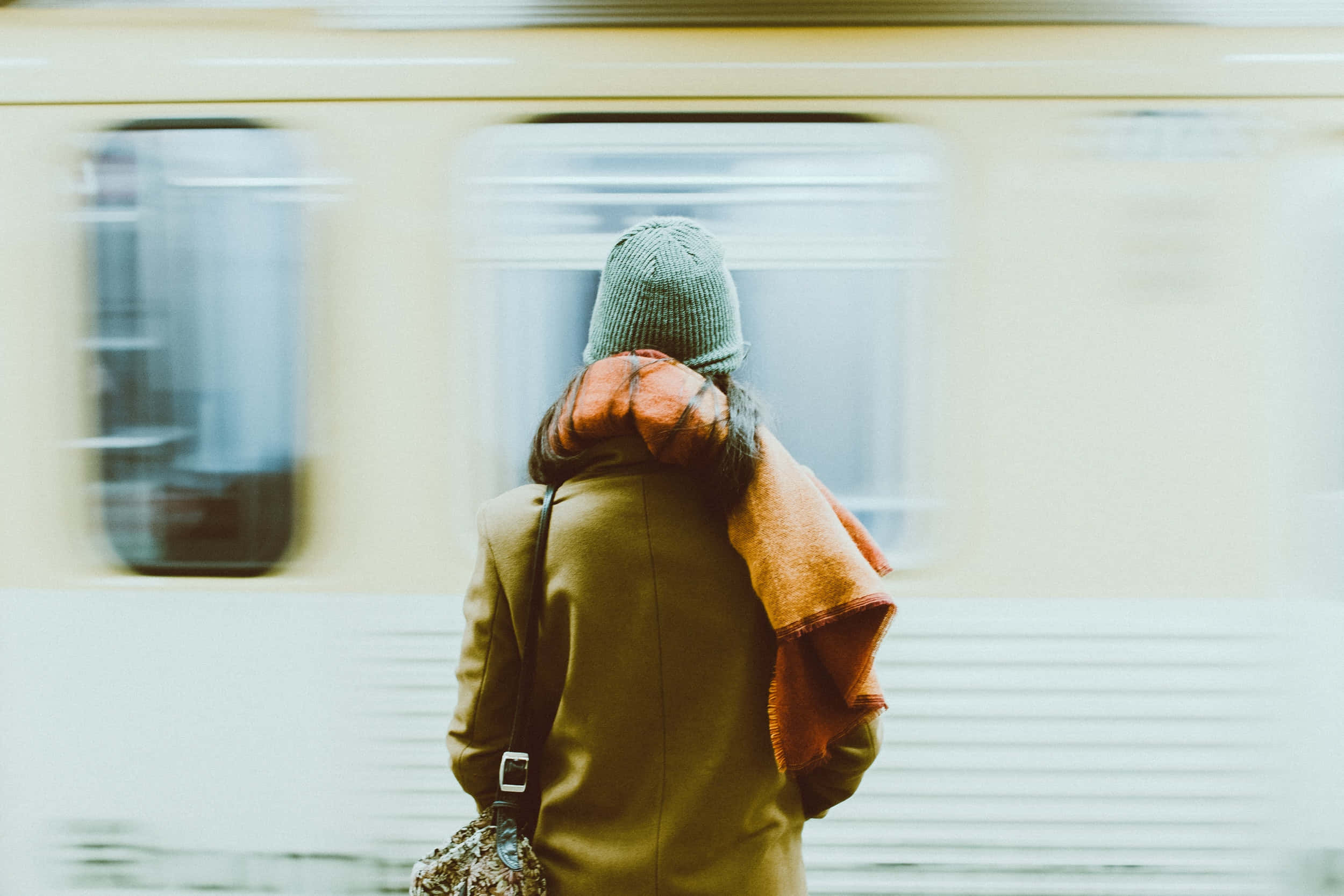 Waiting 桌布 壁紙 — 一個人戴著針織帽和外套站在車站，一列模糊的火車正在移動中經過。