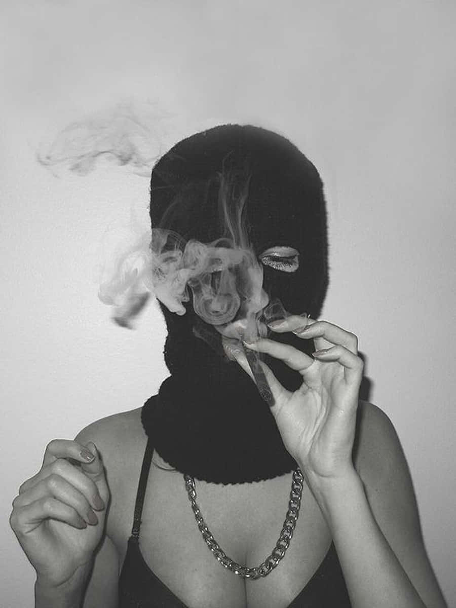 Ski Mask Girl 桌布 壁紙 — 一個人戴著黑色頭套，在單色的普通牆前面吸煙，呼出煙霧。