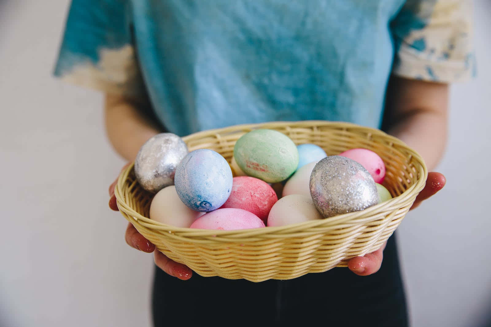 Eggs 桌布 壁紙 — 一個人手持一個編織籃，裡面裝滿了色彩繽紛的手繪復活節蛋，帶有粉彩和閃粉色調。