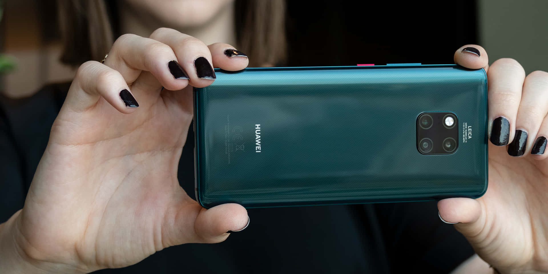 手持青綠色Huawei四鏡頭智慧型手機的特寫。