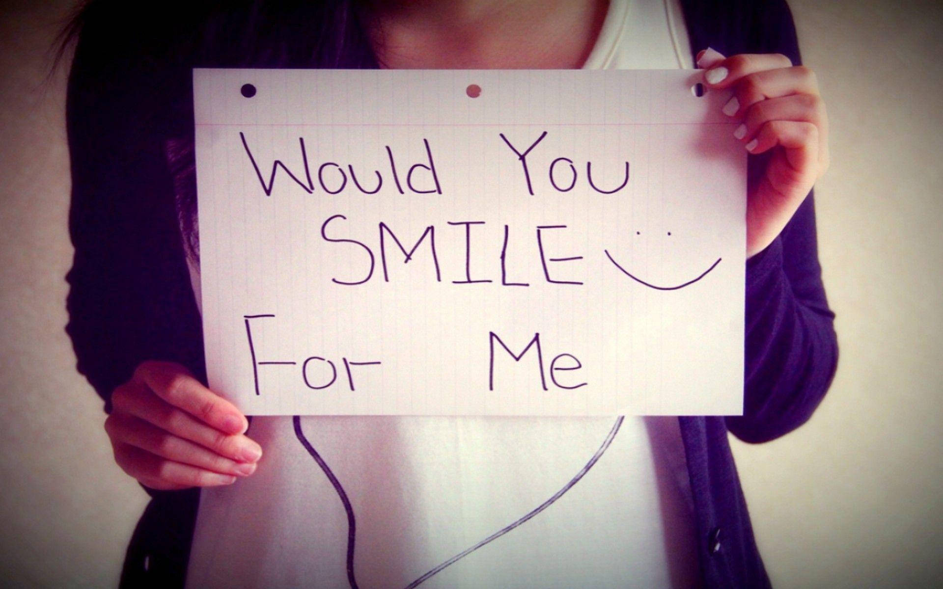 Smile 桌布 壁紙 — 一個人手持手寫標語，上面寫著「你會為我微笑嗎？」並畫有笑臉。