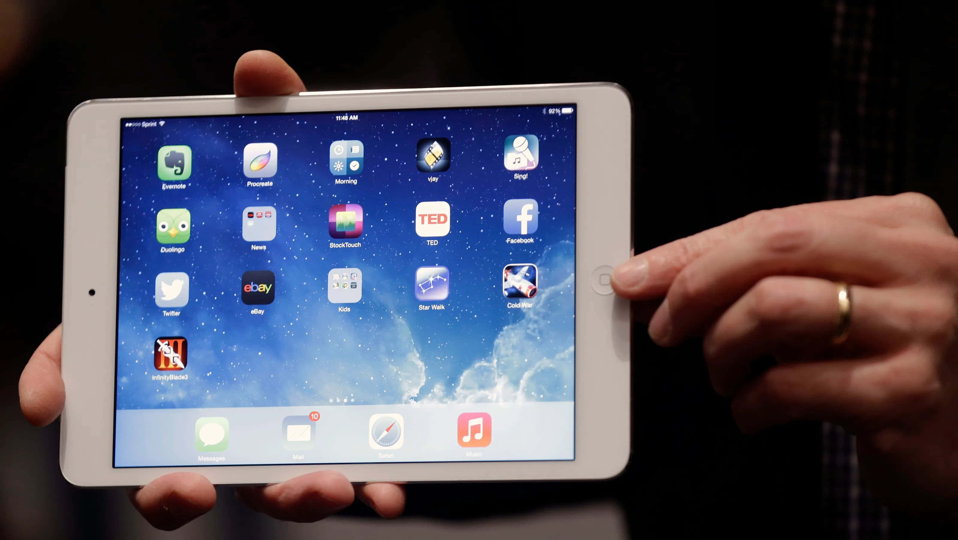 iPad 桌布 壁紙 — 一個人手持白色iPad，顯示星空桌布和應用程式圖示，背景為深色。