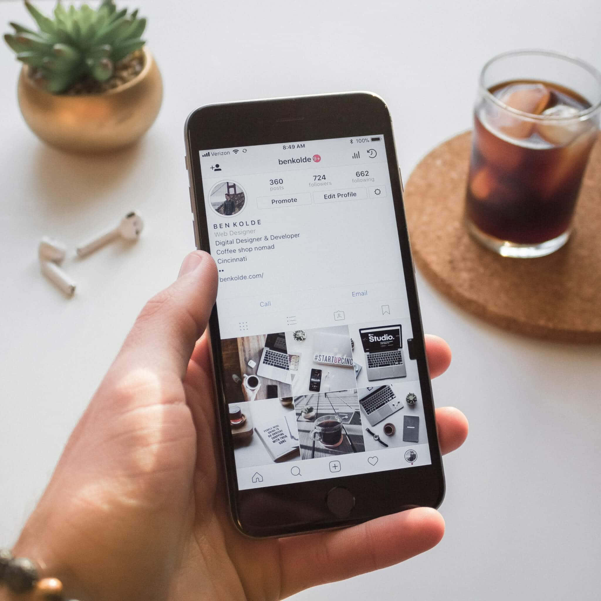 一個人拿著iPhone，螢幕上顯示咖啡杯的照片 壁紙