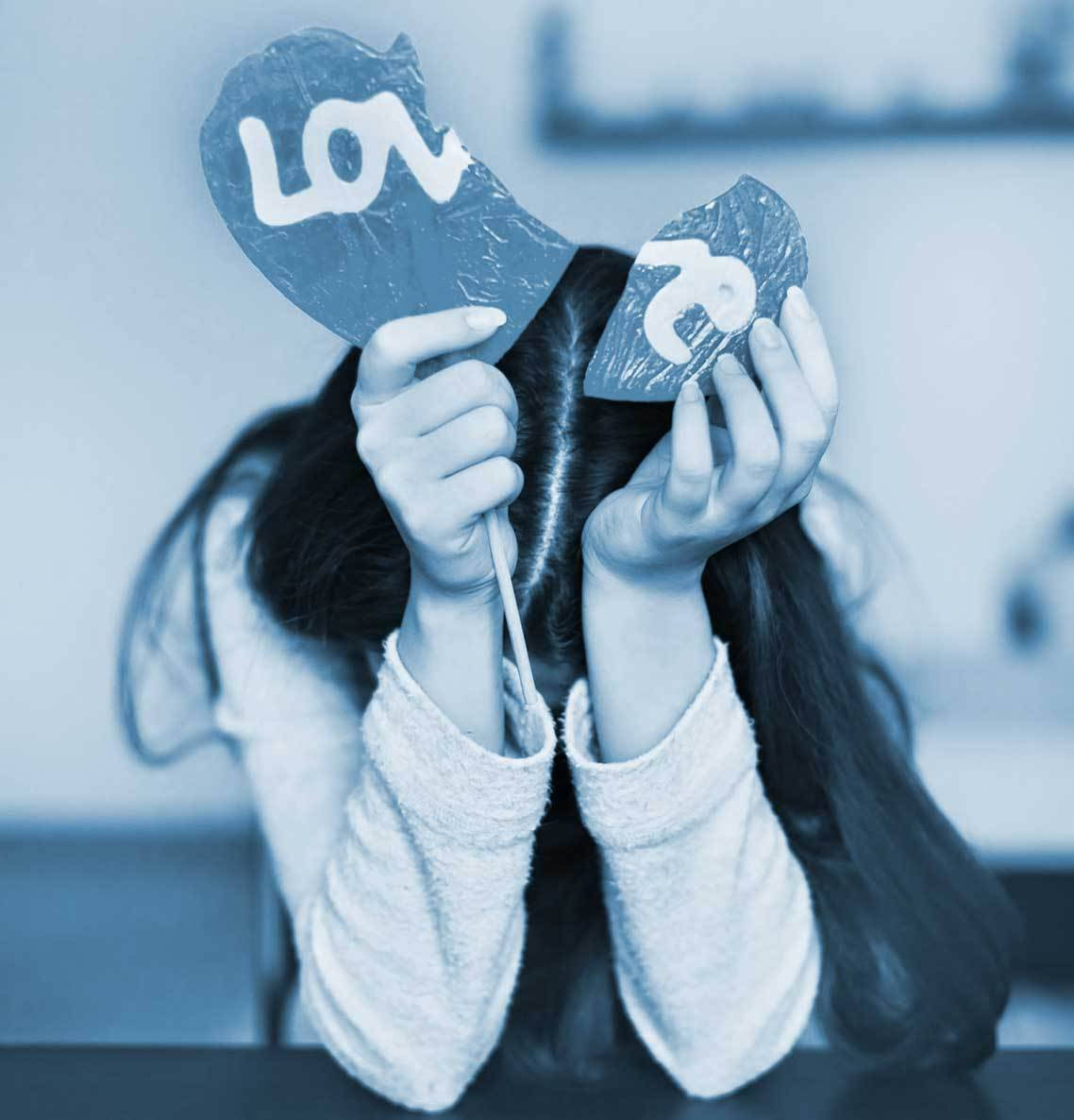 心碎 桌布 壁紙 — 一個人拿著兩塊破碎的心形碎片，在臉上拼出「LOVE」，採用冷藍色單色調。