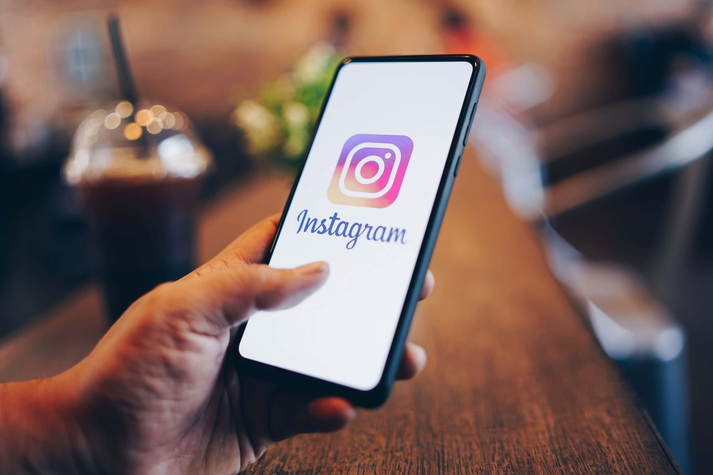 一個人拿著帶有Instagram標誌的手機 壁紙