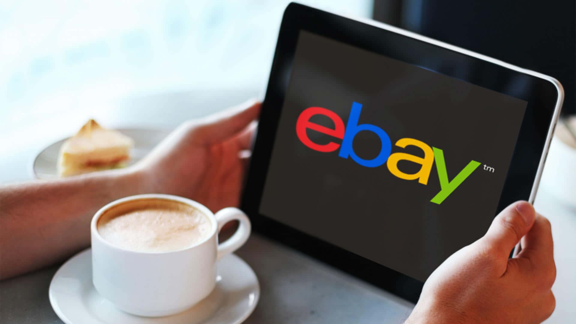 品牌 桌布 壁紙 — 一個人拿著顯示eBay標誌的平板電腦，一邊喝咖啡，旁邊放著一塊蛋糕。