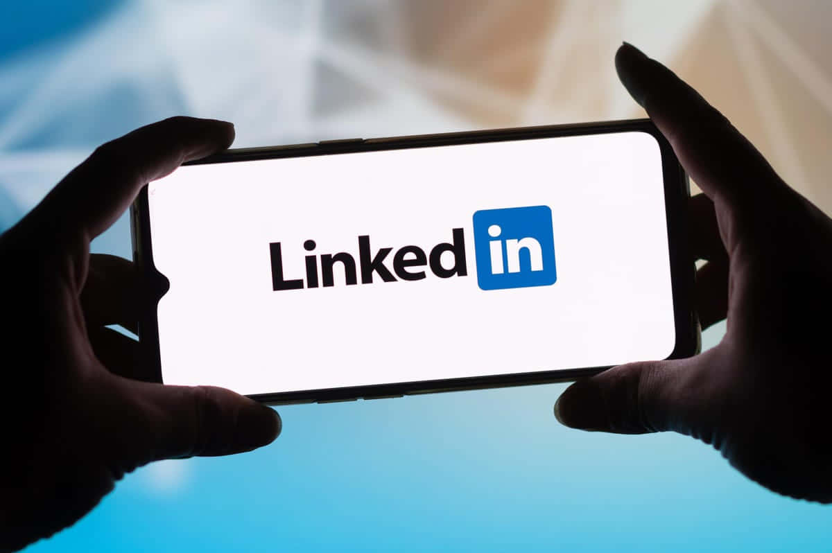 一個人拿著顯示LinkedIn標誌的手機 壁紙