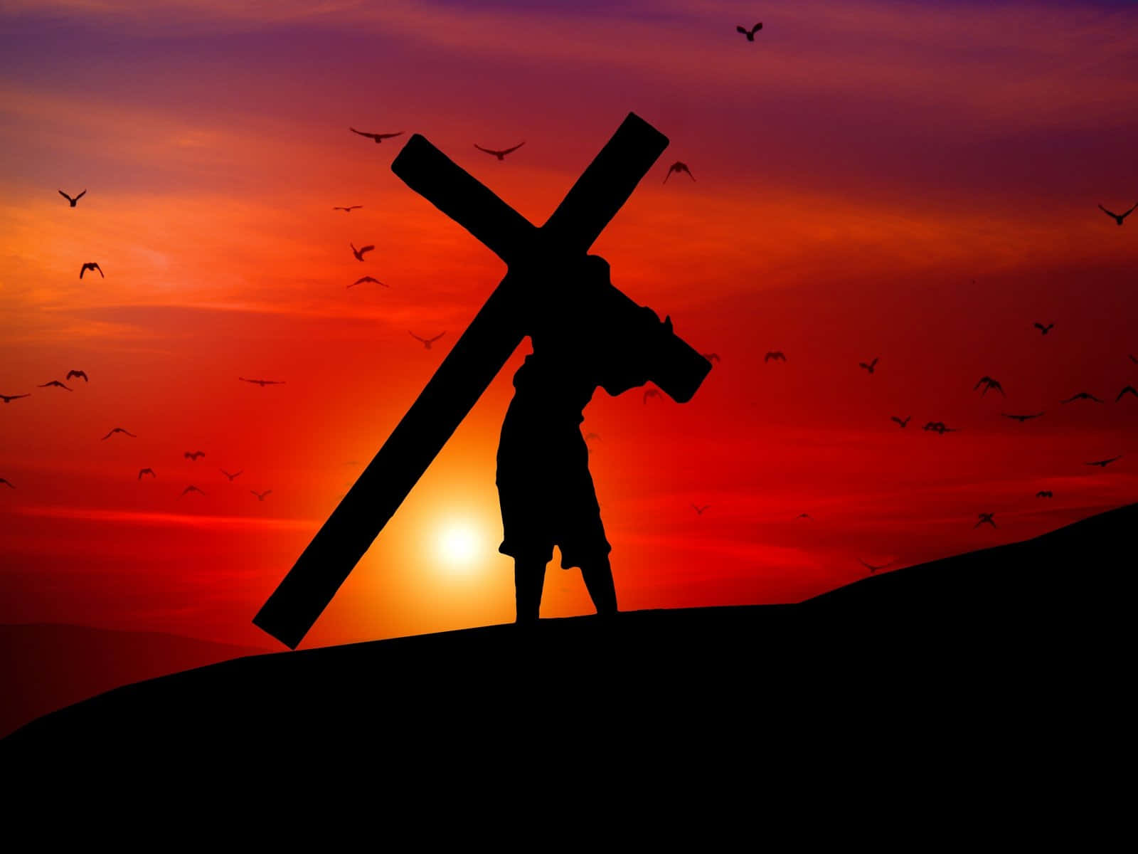 Jesus Crucifixion 桌布 壁紙 — 一個人物的剪影，在山頂上扛著一個大十字架，背景是火燒般的日落天空，有鳥兒飛翔。