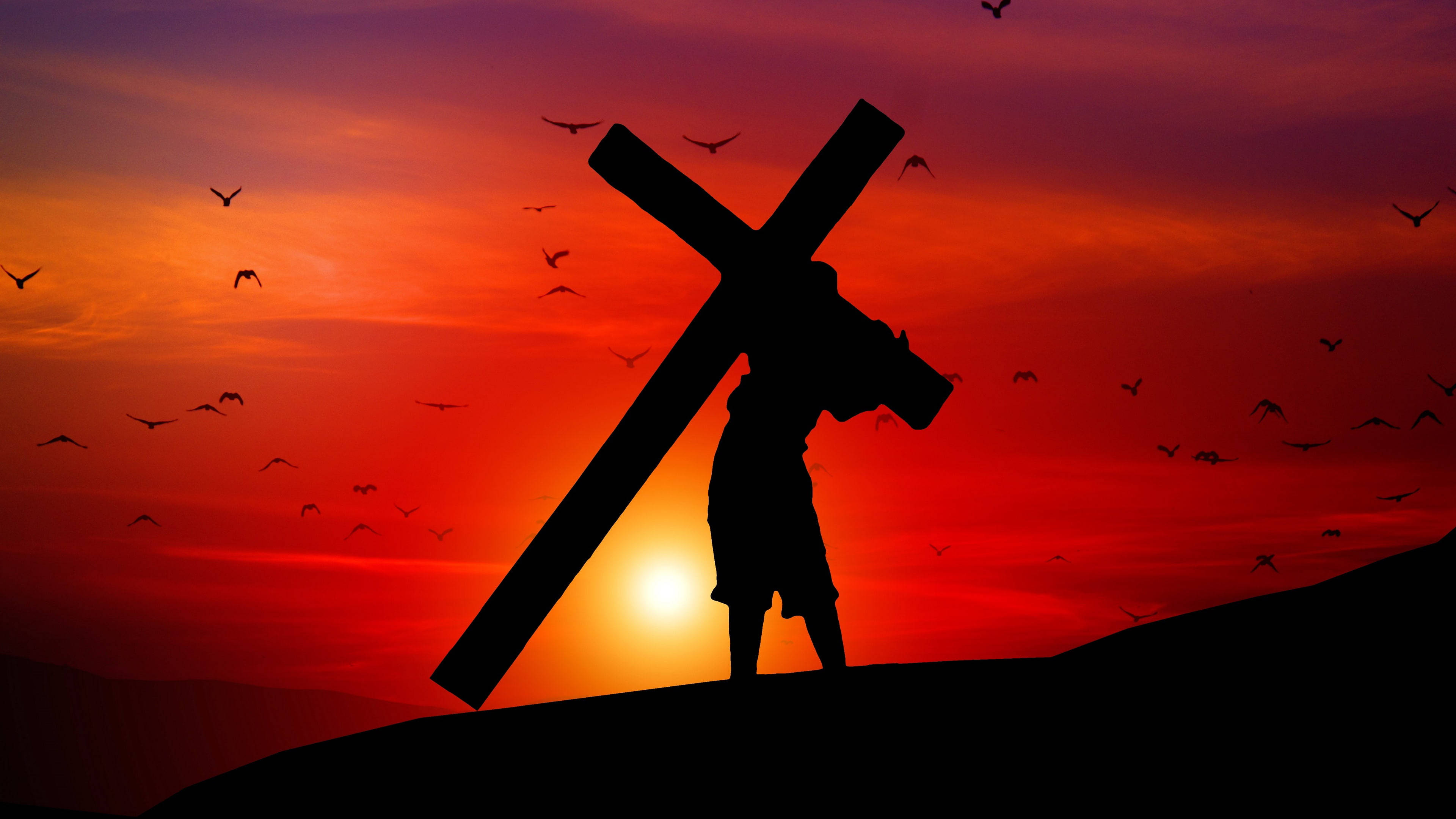 Christ 桌布 壁紙 — 一個人物背負著一個大十字架在山頂上，背景是火紅的日落天空，有鳥兒飛翔的剪影。