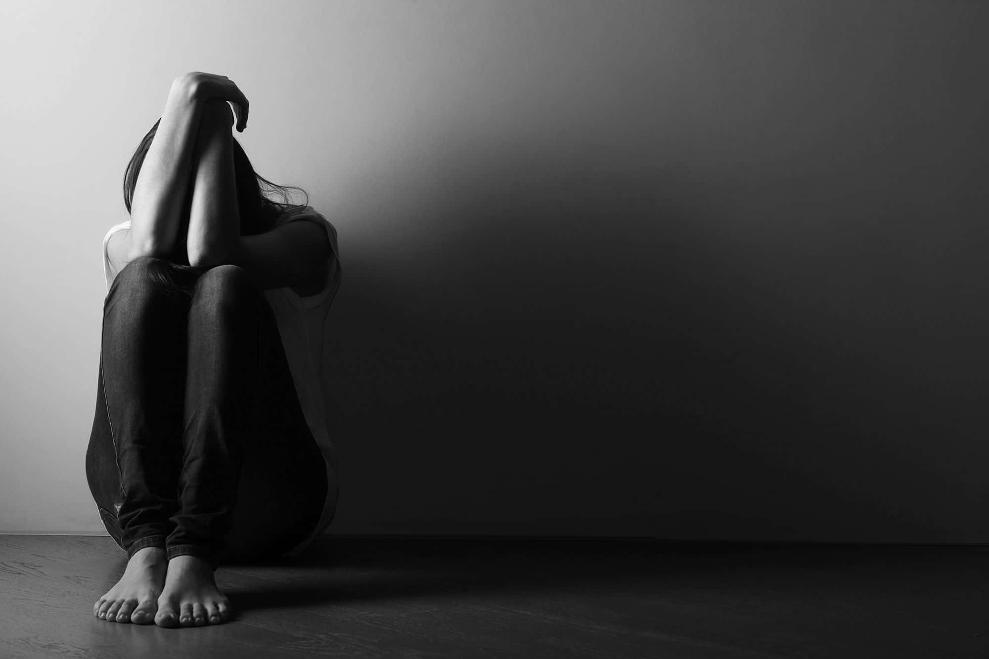 Depressed 桌布 壁紙 — 一個人獨自坐在昏暗的房間裡，彎腰用雙臂遮住臉，陷入無聲的絕望。