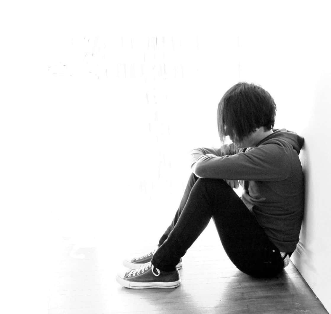 Sad Romance 桌布 壁紙 — 一個人獨自坐在木地板上，靠著明亮的牆壁，呈現出鮮明的黑白照片效果。
