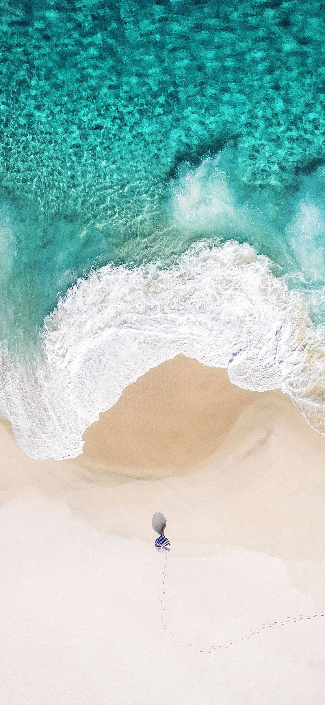 waves 桌布 壁紙 — 一個人獨自走在純白沙灘上，朝著碧綠海浪的航拍視圖。