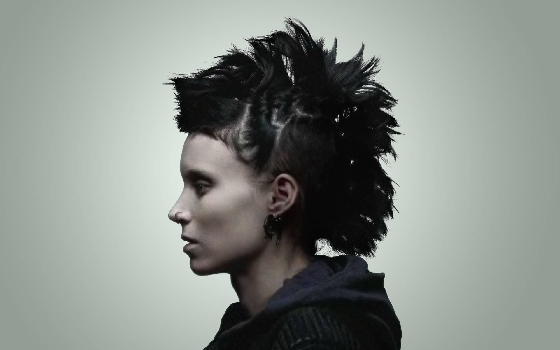 Rooney Mara 桌布 壁紙 — 一個人留著戲劇性的黑色莫西乾髮型，側面展示在純灰色背景前。