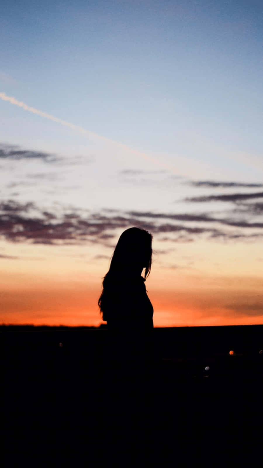 Sunset Silhouette 桌布 壁紙 — 一個人的剪影，凝視著充滿活力的日落，橙色和藍色的天空被雲彩劃過。