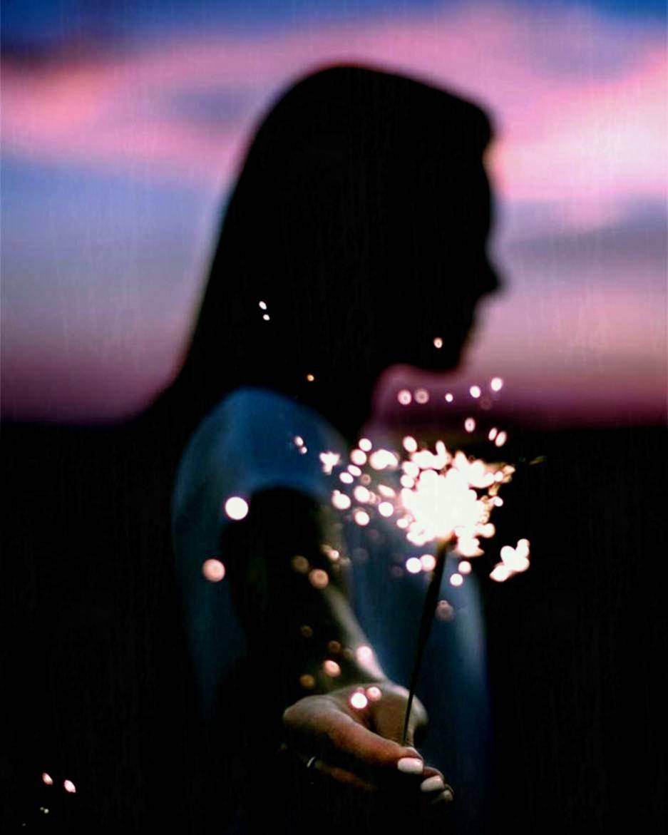 Fireworks 桌布 壁紙 — 一個人的剪影，在帶有粉紅色和紫色色調的暮色天空中手持閃閃發光的煙火。