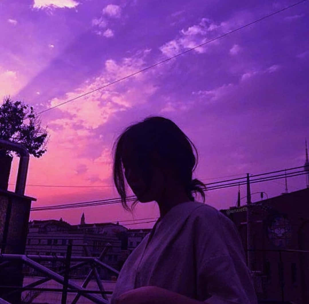 Silhouette 桌布 壁紙 — 一個人的剪影，在有電線的城市景觀上凝視著充滿活力的紫色和粉紅色日落。